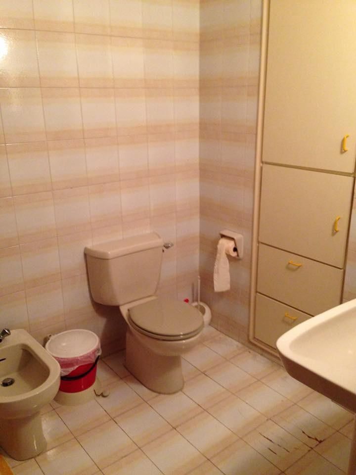 Bathroom before renovation with dated pink-striped tiles and beige fittings