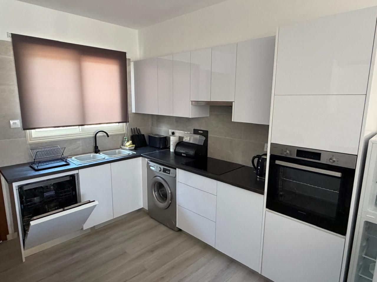Renovated kitchen with white cabinets and dark worktops