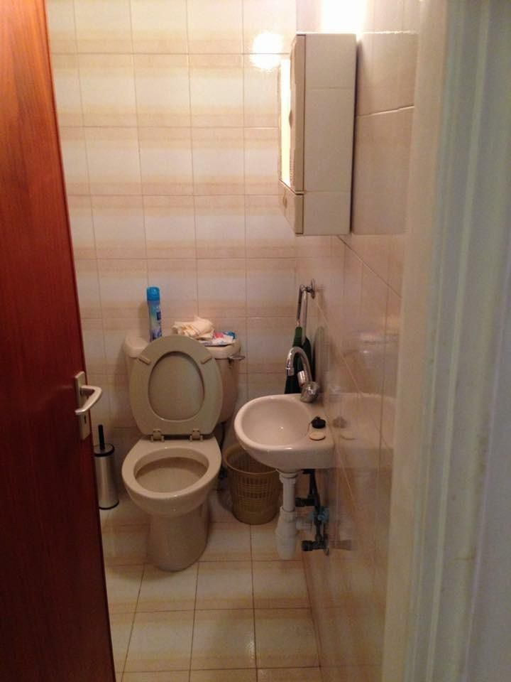 Small toilet room before renovation with dated tiles and older fittings