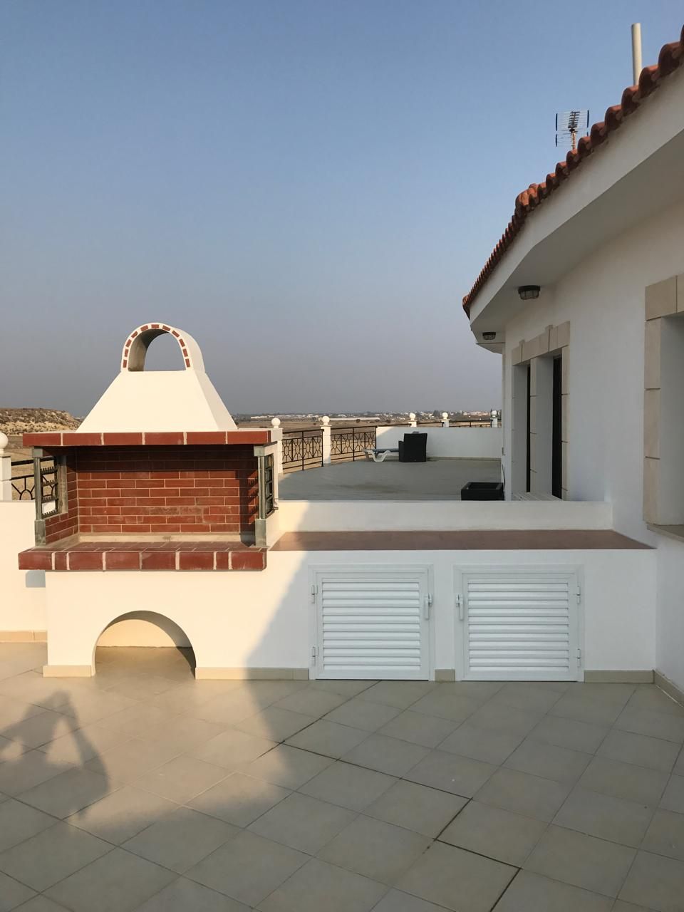 Completed built-in BBQ with tiled worktop and white storage cupboards on the penthouse roof terrace