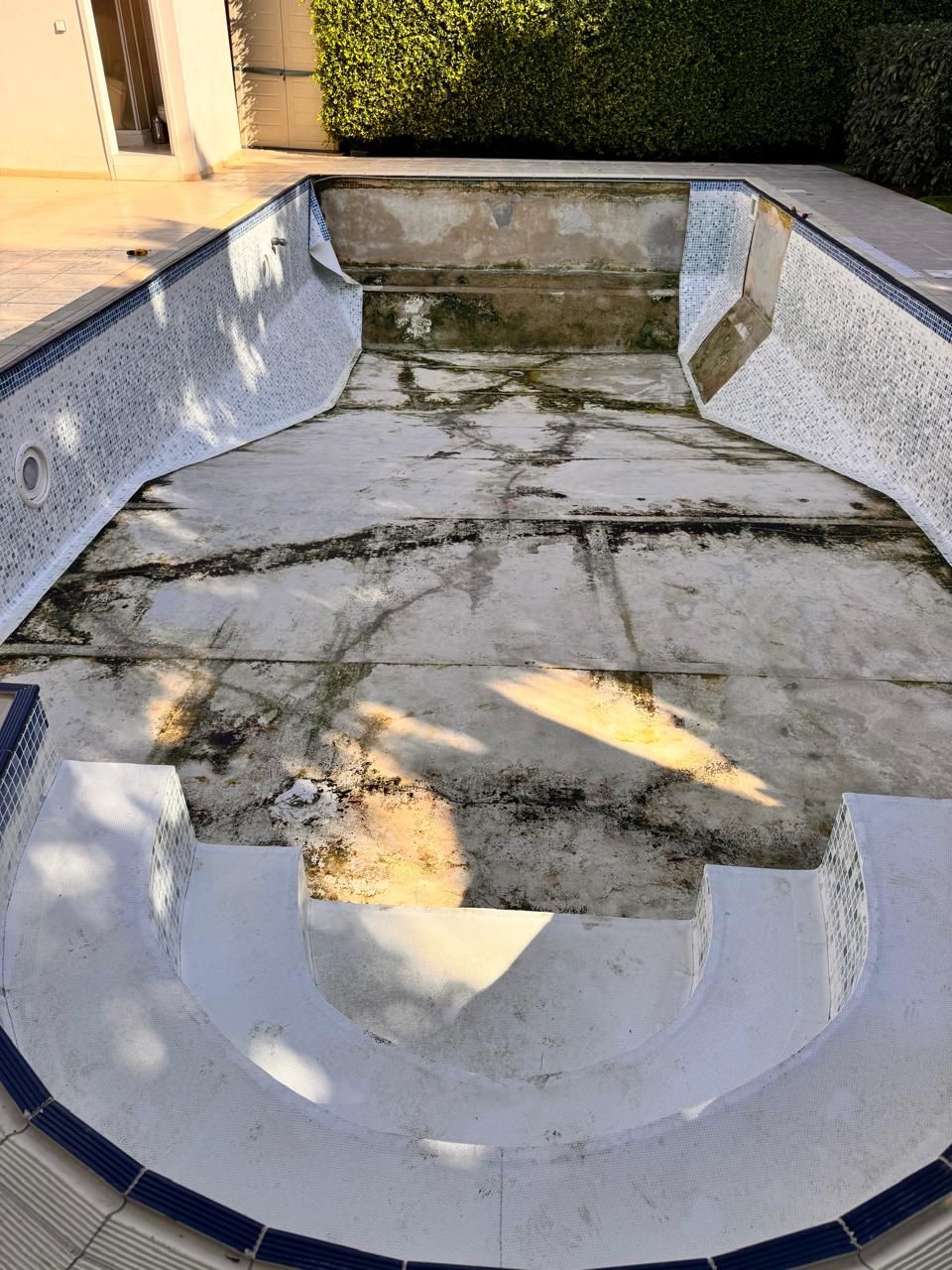 Old pool liner being removed from the walls of the leaking pool
