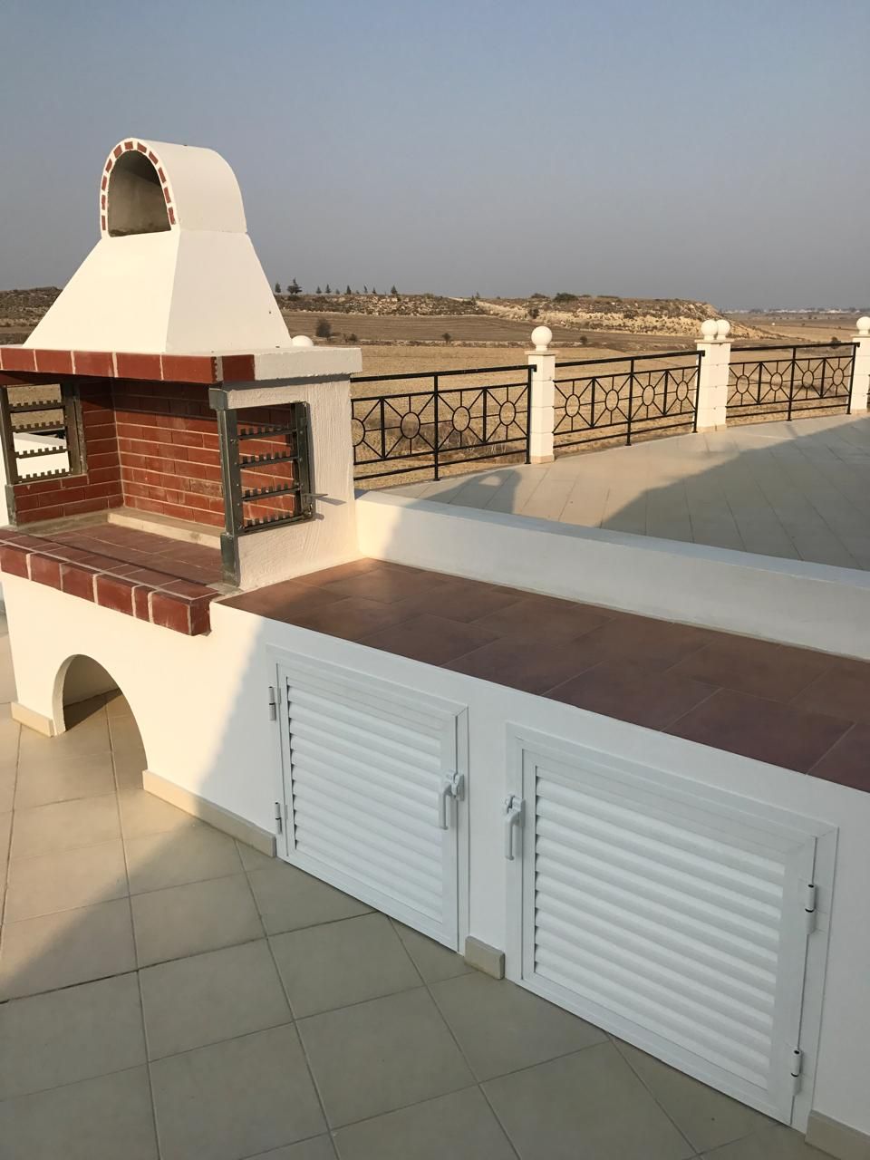 Close-up of the finished brick barbecue, tiled outdoor counter and louvred cupboard doors