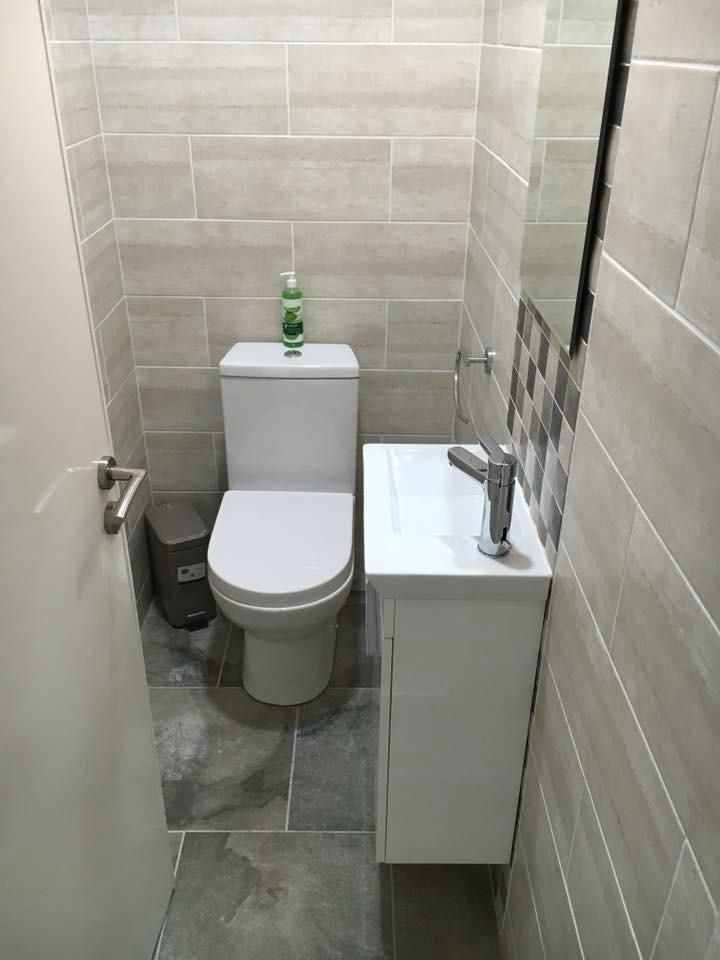 Renovated toilet room with grey tiling, a new toilet and white vanity unit