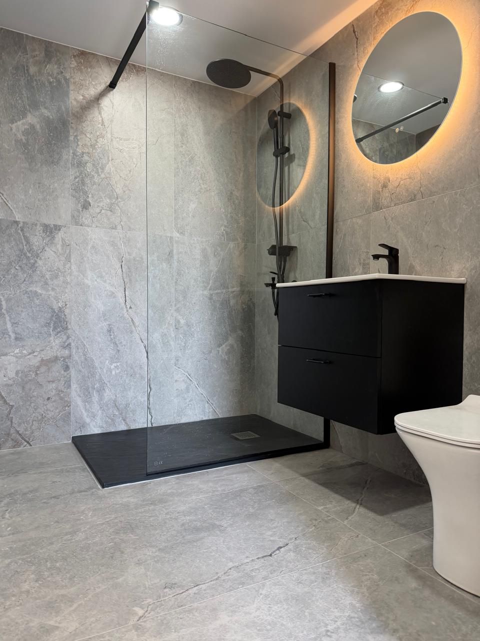 Completed walk-in shower with grey stone-effect tiles and black fittings