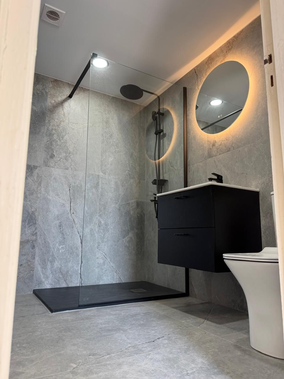 Completed bathroom with walk-in shower and illuminated mirror